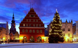 Historischer Marktplatz im Winter mit Weihnachtsbaum und beleuchtetem Gebäude.