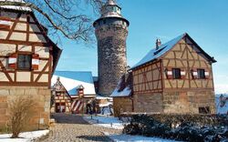 Nürnberger Burg im Winter mit blauem Himmel und schneebedeckten Fachwerkgebäuden.