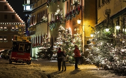 Weihnachtlich beleuchtete Straße mit Menschen im Schnee in Rothenburg ob der Tauber.
