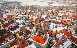 Stadtansicht im Winter mit schneebedeckten Dächern und bunten Häusern aus der Luftperspektive.