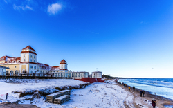 Hotel am verschneiten Strand mit blauem Himmel und Spaziergängern.