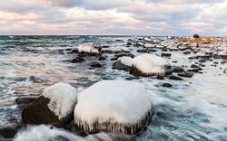 Vereiste Felsen am Ufer der winterlichen Ostsee unter bewölktem Himmel.