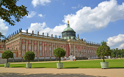 Barockes Gebäude mit Kuppel und Statuen, umgeben von Gartenanlagen.