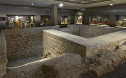 Ein antiker Keller mit Steinmauern und Vitrinen voller Artefakte.