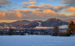 Verschneite Landschaft mit Bergen und Wolken am Horizont.