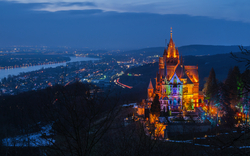 Beleuchtetes Schloss bei Nacht mit Fluss im Hintergrund