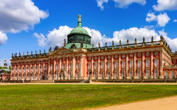 Historisches Schloss mit Kuppel vor blauem Himmel.