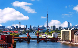 Skyline von Berlin mit Fernsehturm und Spree bei blauem Himmel.