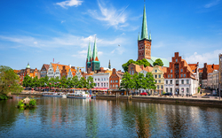 Stadtansicht mit historischen Gebäuden und Kirchtürmen am Wasser.