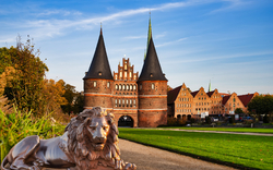 Lübecker Holstentor mit Löwenstatue im Vordergrund, historisches Stadttor in Lübeck, Deutschland.