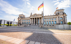 Das Reichstagsgebäude in Berlin mit wehender deutscher Flagge.