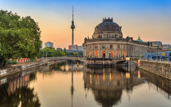 Blick auf Berliner Fernsehturm und Bodemuseum bei Sonnenaufgang, Spiegelung im Wasser.