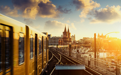 Zug fährt bei Sonnenuntergang über eine Brücke in der Stadt.