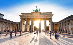 Menschen vor dem Brandenburger Tor bei tiefstehender Sonne.