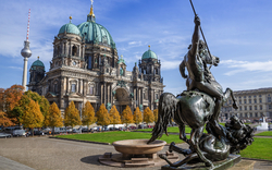 Berliner Dom und Neptunbrunnen-Statue an einem sonnigen Tag.
