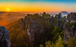 Felsformationen im Sonnenaufgang mit Wald und Brücke im Hintergrund