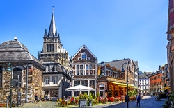 Historische Gebäude und Straßencafé bei sonnigem Wetter.