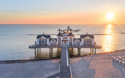 Seebrücke mit Pavillon bei Sonnenuntergang am Strand.
