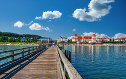 Holzsteg am Meer mit Blick auf Gebäude und bewölkten Himmel