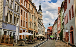 Häuserreihe in einer historischen europäischen Altstadt mit Kirche im Hintergrund.