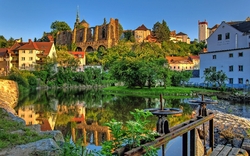 Ruine der Nikolaikirche in Hammermühle im Sommer, umgeben von Grün und Wasser.