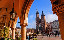 Marktplatz mit Menschen und St. Marienkirche in Krakau bei sonnigem Wetter.