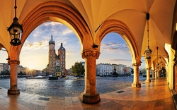 Bogenarkaden mit Blick auf den Marktplatz und Kirche bei Sonnenaufgang.