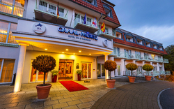 Eingang eines modernen Hotels mit großen Fenstern und Pflanzgefäßen.
