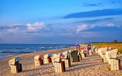 Strand mit Strandkörben und blauem Himmel.