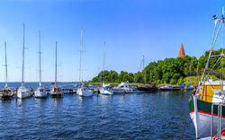 Boote im Hafen an einem sonnigen Tag mit Kirche im Hintergrund.