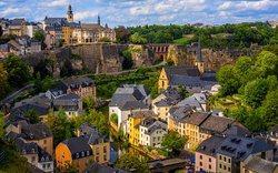 Stadtansicht von Luxemburg mit historischen Gebäuden und grüner Landschaft.