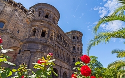Alte Steinruine mit roten Rosen und blauem Himmel im Hintergrund.