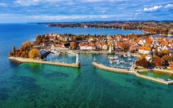 Luftaufnahme einer Hafenstadt mit Seen und herbstlichen Bäumen.