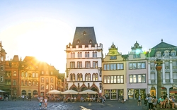 Historische Gebäude auf einem sonnigen Platz mit Menschen.
