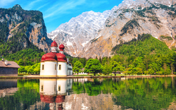 Kirche St. Bartholomä am Königssee mit Bergen im Hintergrund.