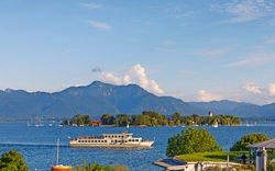 See mit Passagierschiff vor Bergkulisse im Hintergrund.
