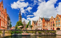 Historische Gebäude an einem Kanal in Brügge unter einem blauen Himmel.