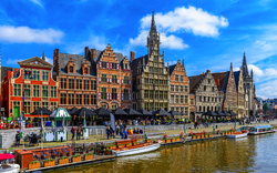 Historische Gebäude am Flussufer mit Booten und blauem Himmel.