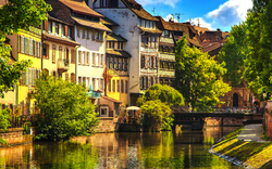 Historische Gebäude entlang eines Kanals in Straßburg, Elsass, bei klarem Himmel.
