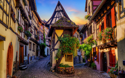 Fachwerkhäuser in einer malerischen Straße in Eguisheim, Elsass, Frankreich bei Sonnenuntergang.