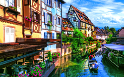 Bunte Fachwerkhäuser am Kanalrand, ein Boot fährt im Wasser vorbei.