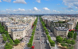 Blick auf die Champs-Élysées in Paris, gesäumt von Bäumen und Gebäuden bei klarem Himmel.