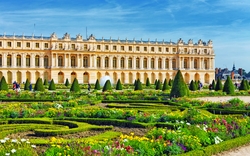 Barockgarten mit bunten Blumen vor einem historischen Gebäude im Hintergrund.