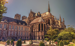 Mittelalterliche Kathedrale mit Garten und Personen im Vordergrund an einem sonnigen Tag.