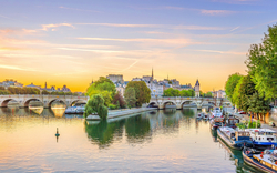 Sonnenaufgangsansicht der Skyline der Altstadt von Paris mit der Seine und Flusskreuzfahrtschiffen.