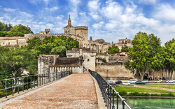 Brücke in Avignon mit altem Gebäude im Hintergrund an einem sonnigen Tag.