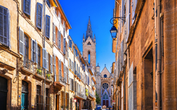Malerische Gasse in Aix-en-Provence mit Blick auf eine Kirche im Hintergrund.