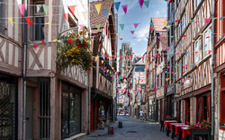 Gasse mit Fachwerkhäusern und Wimpelgirlanden, Tische im Freien.