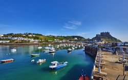 Boote im Hafen mit Burg im Hintergrund bei blauem Himmel