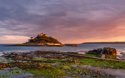 Insel mit Schloss bei Sonnenuntergang und Meer im Vordergrund